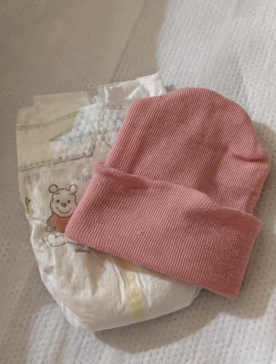 A pink newborn hat and diaper