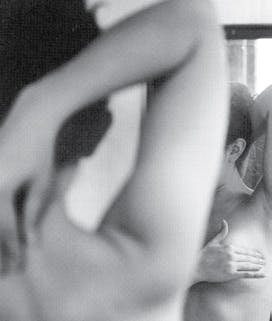 Black and white photograph of a woman giving herself a breast exam.