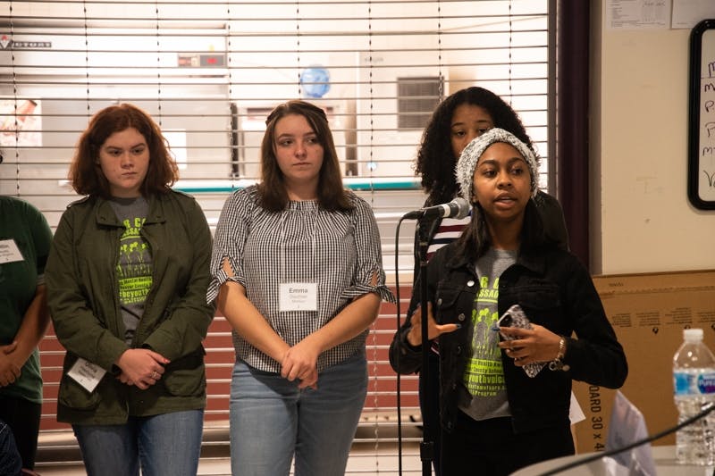 Youth speaking at an event into a microphone.